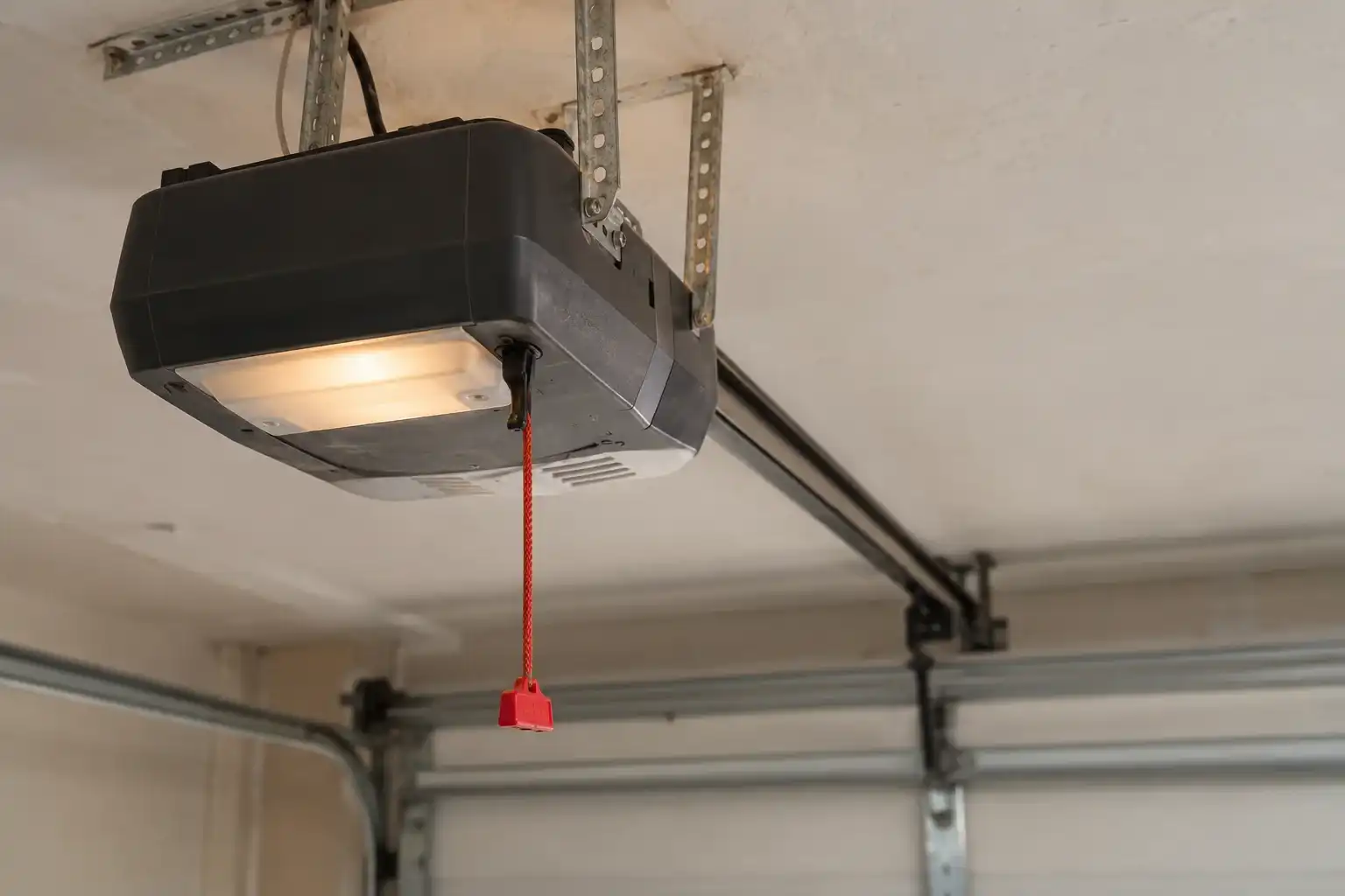 Garage door opener motor and rail on the ceiling with the red release cord
